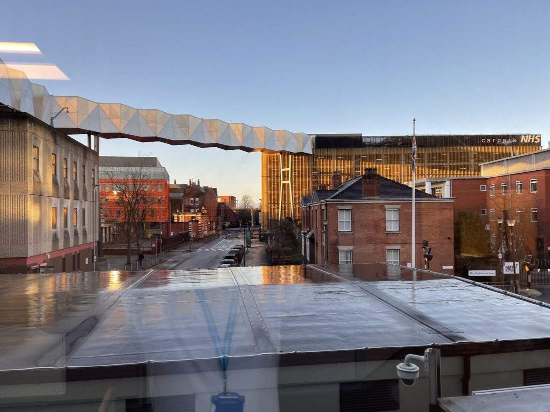 Manchester Royal Infirmary at golden hour, with the Oxford Road skybridge